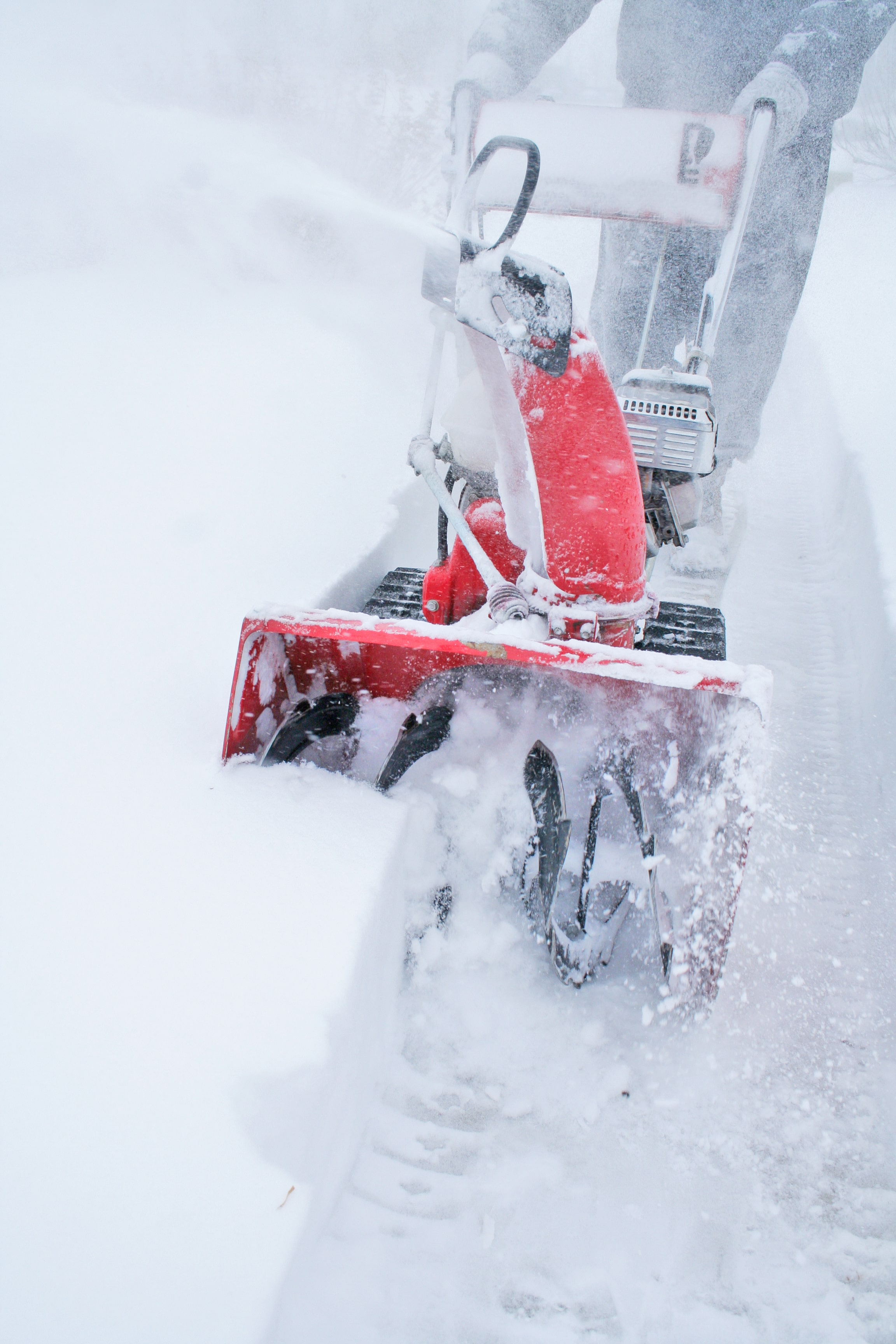 Person using snow blower to clear deep snow on a driveway