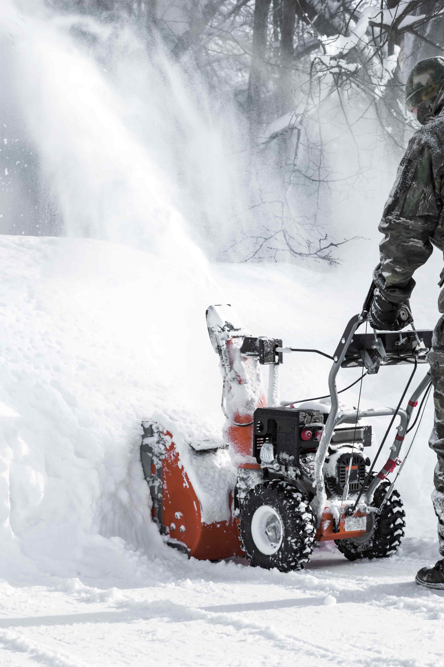 Person operating snow blower in heavy snow-covered area.